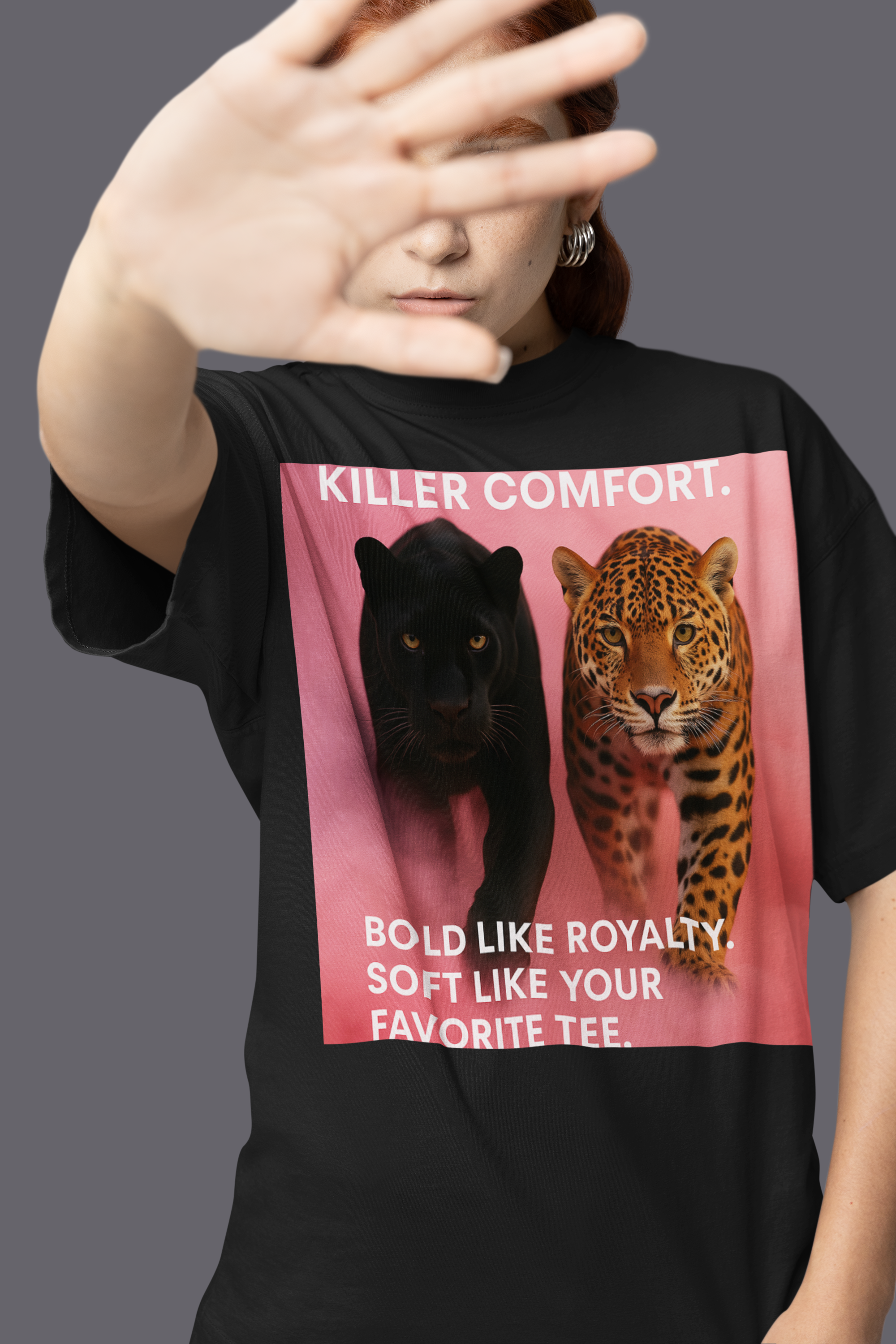 Woman wearing a black graphic T-shirt featuring a black panther and a Jaguar with the text " Killer Comfort. Bold like royalty. Soft like your favorite tee" on a Pink background.